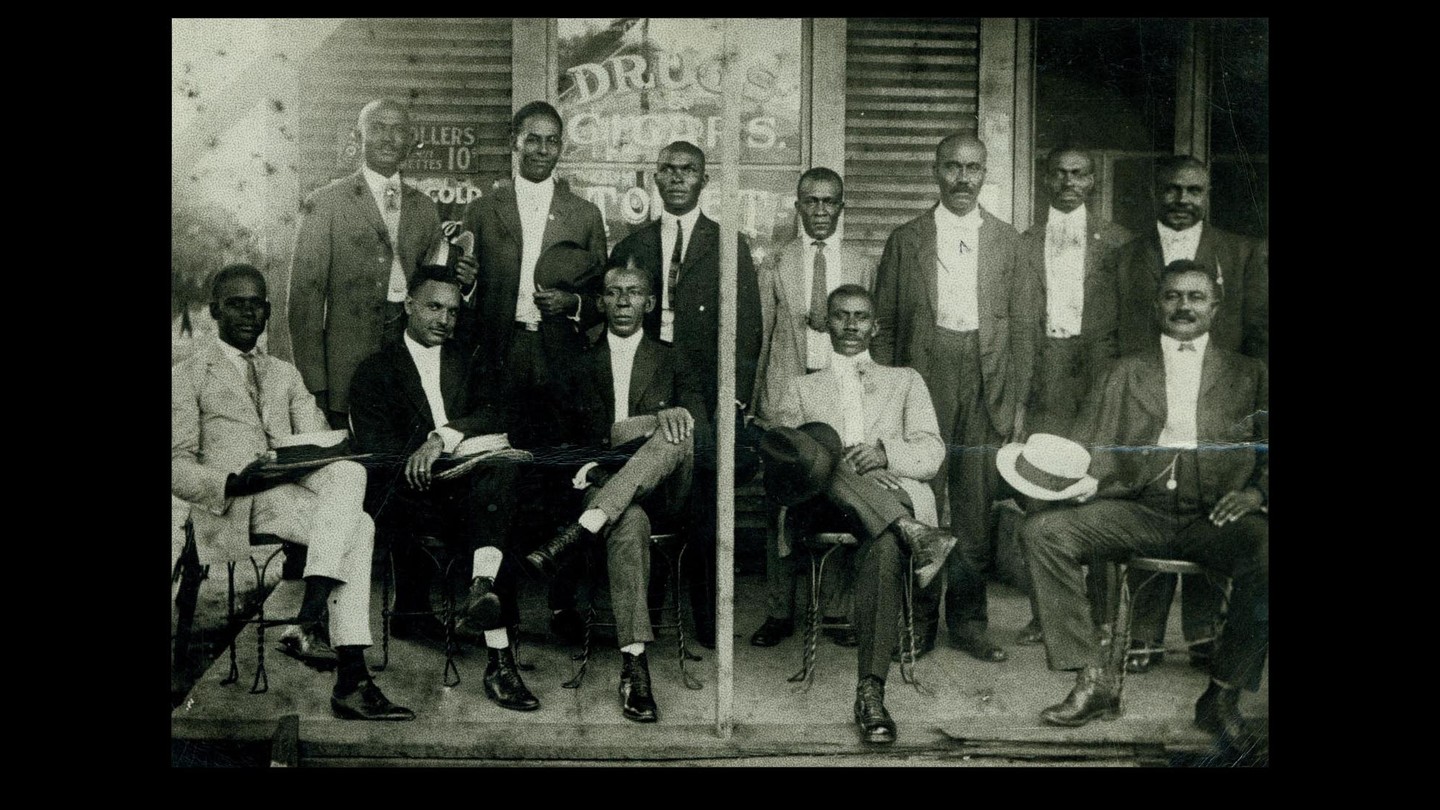 Men in suits sitting outside a drugstore