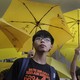 Joshua Wong stands in front of yellow umbrellas, the symbol of the 2014 Hong Kong protests, ahead of a 2015 court hearing.