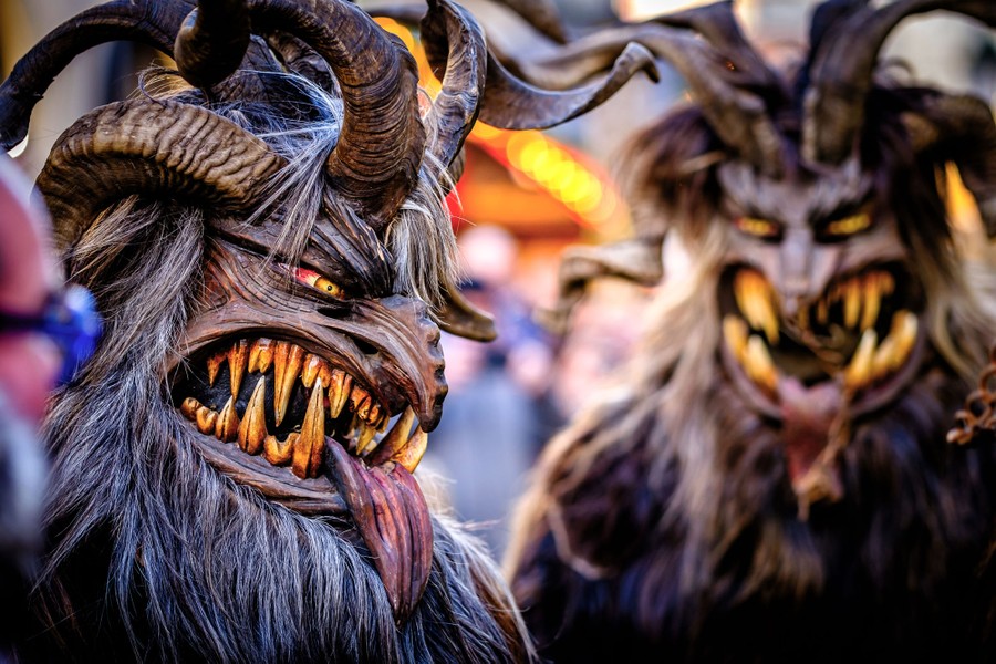 Two performers wearing frightening wooden masks with long horns