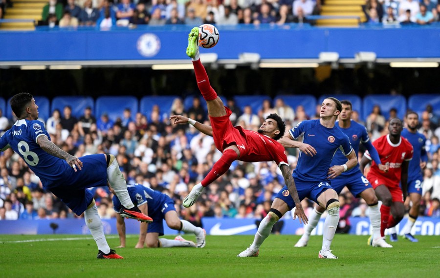 A player performs a bicycle kick in mid-air during a soccer match.