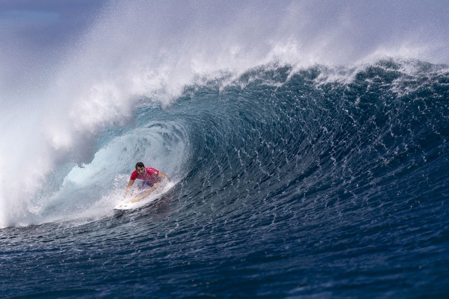 A surfer rides a large curling wave.