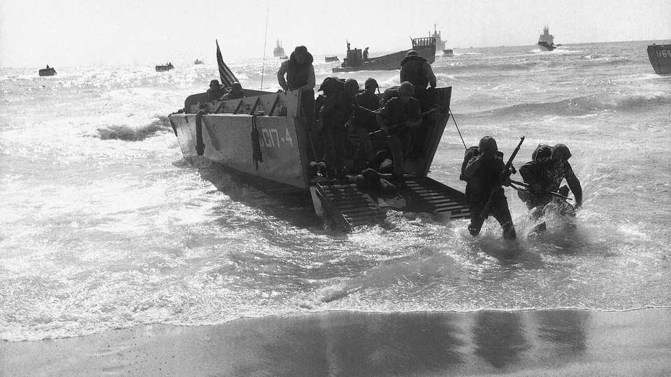 Marines in the process of disembarking from a ship onto a beach.