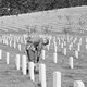 A black and white photograph of a soldier bowing before a hill of gravestones