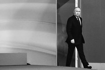 Black-and-white photo of Vladimir Putin in a black suit walking into a room