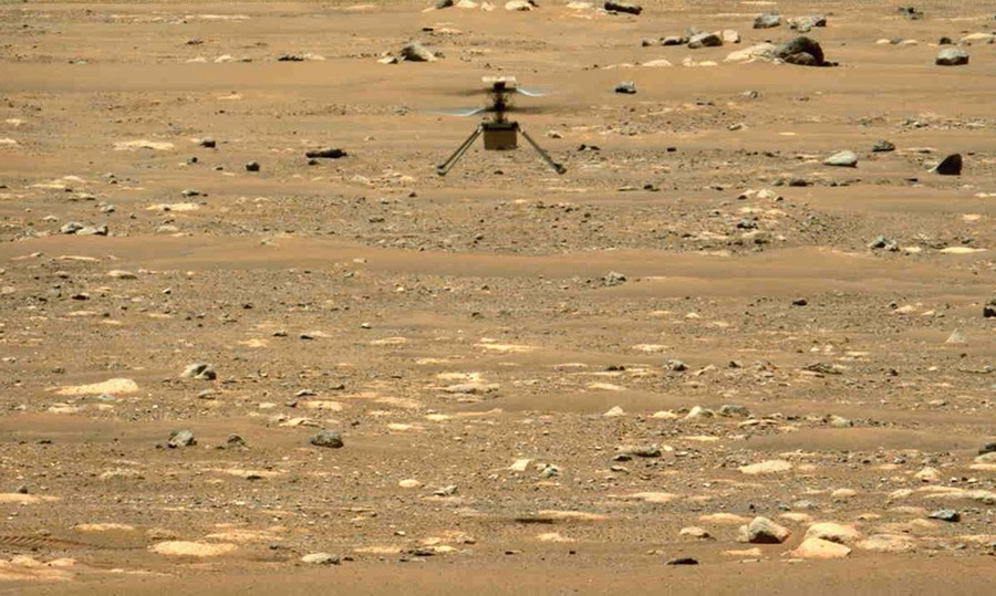A tiny helicopter flies above the dusty surface of Mars.