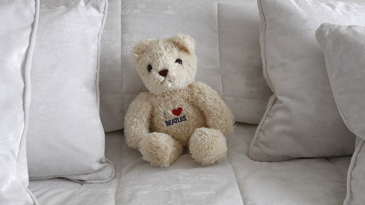 A teddy bear on a bed surrounded by pillows