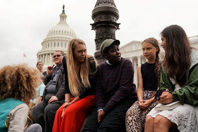 A group of people gather around climate activist Greta Thunberg in front of the U.S. Capitol