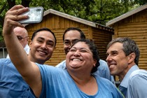 A woman wearing blue takes a selfie with three men also wearing blue