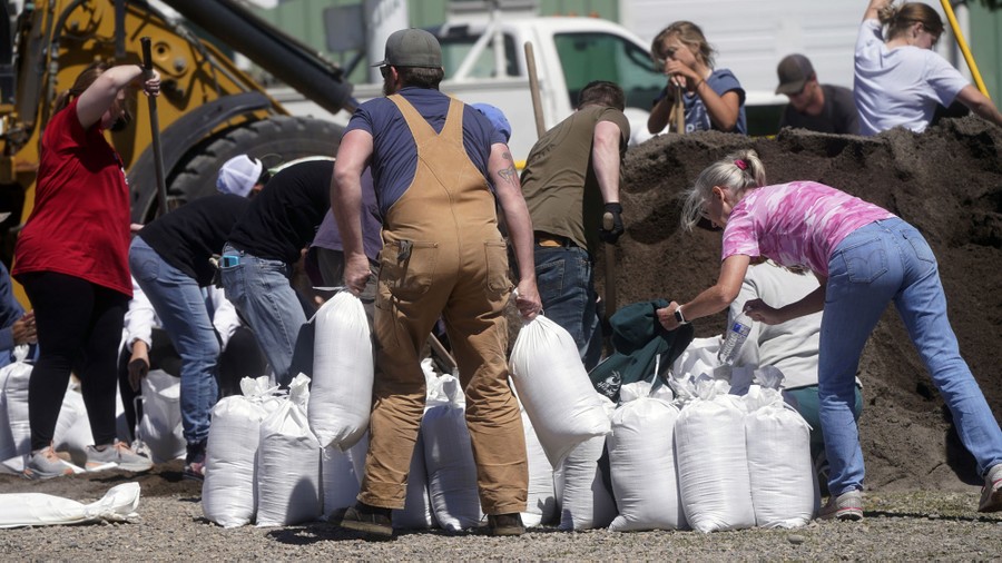 About a dozen people are seen working to fill sandbags.