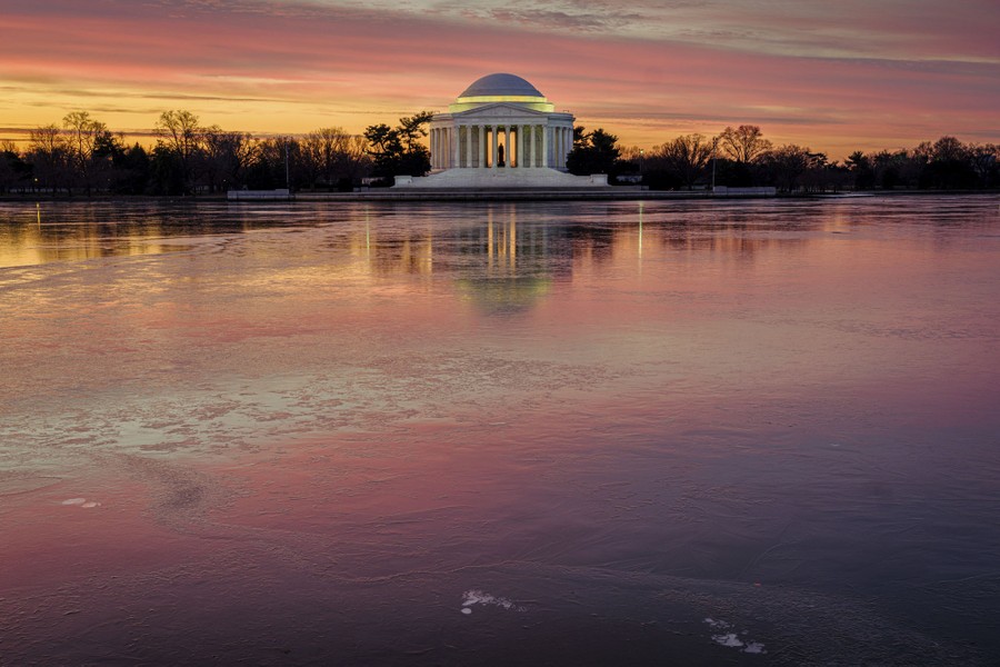 Sunrise reflects off the frozen surface of the Tidal Basin in front of the Jefferson Memorial.