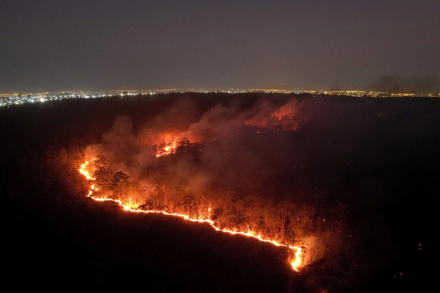 An aerial night view of a line of wildfires burning in a forest