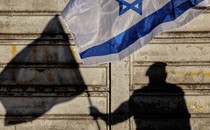 A photo of a silhouette of a man holding an Israeli flag