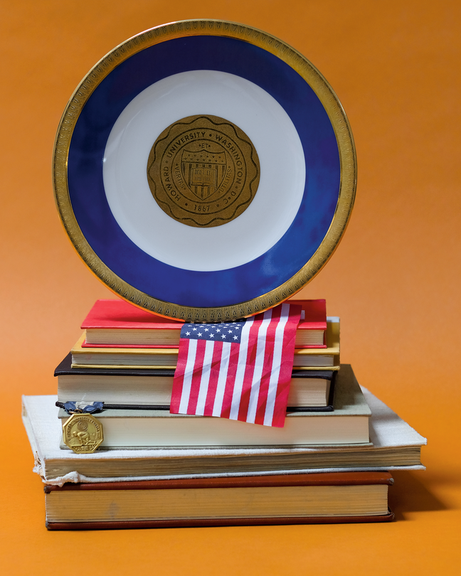 photo of stack of books, American flag, medal and plate from Howard University on orange background