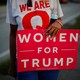 A woman holding a "Woman for Trump" sign.