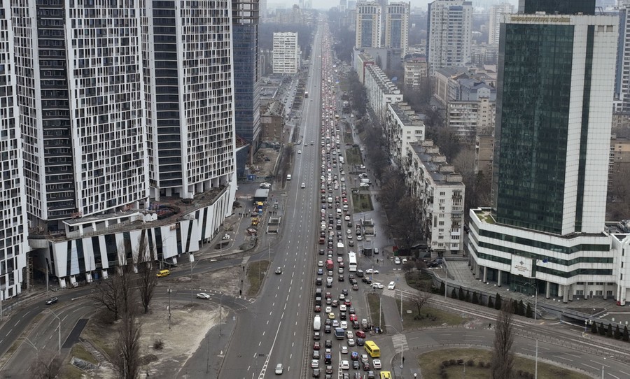 An aerial view of long lines of cars filling one side of a main city street