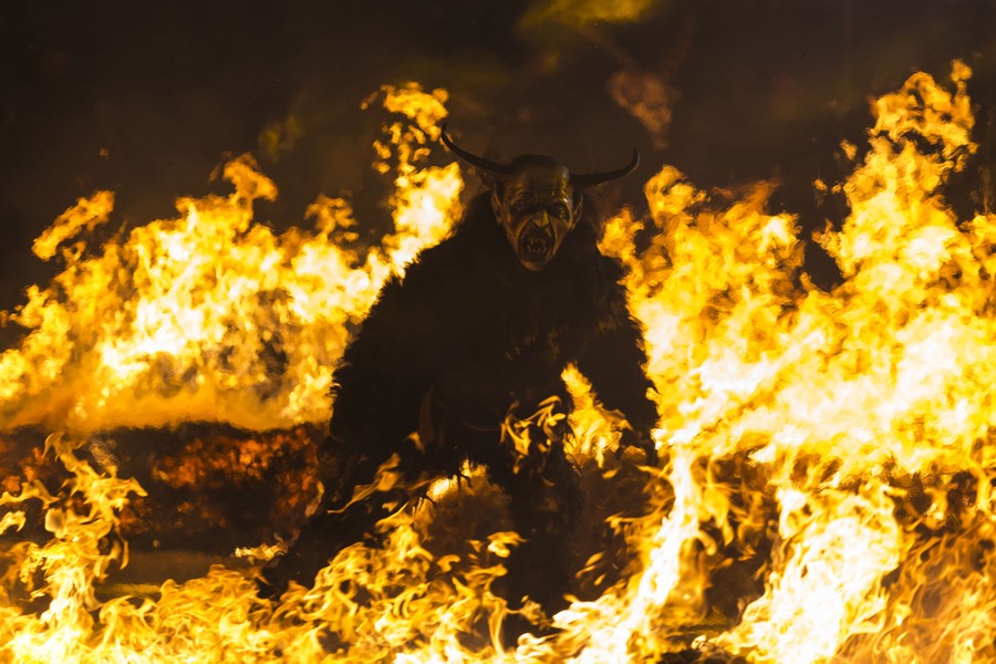 A performer dressed as an evil Krampus character walks among flames.
