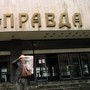 A man shows the headline of the 'Pravda' in front of the entrance of the building of the Soviet newspaper.