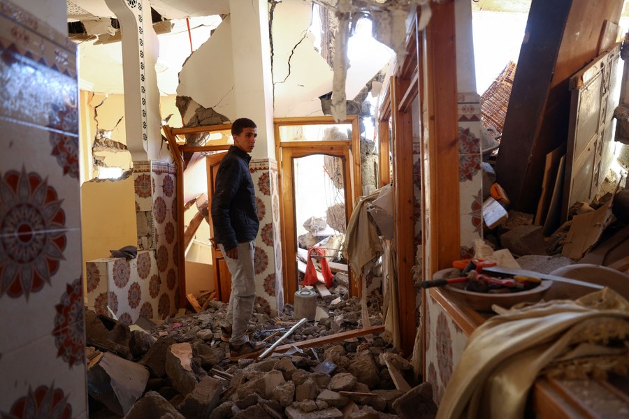 A young man walks through a heavily quake-damaged house.