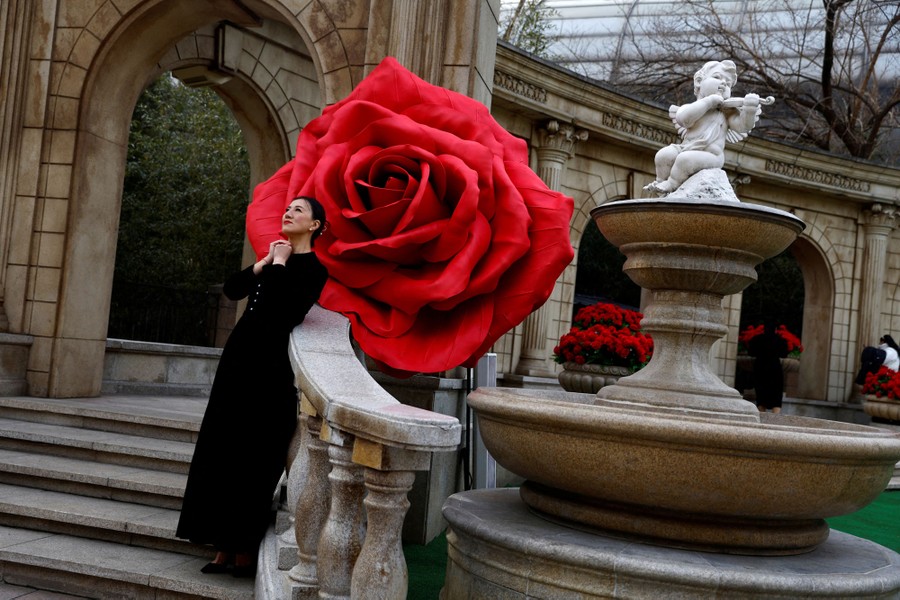 A woman poses in front of a giant rose installation.