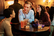 photo of 3 people talking and drinking pints at small round table in pub