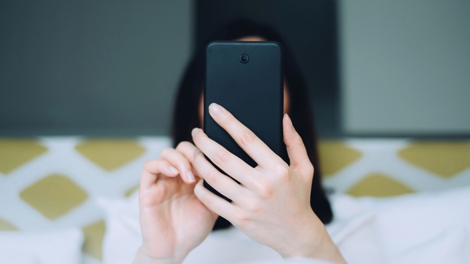 photograph of a woman using phone, held directly in front of her face