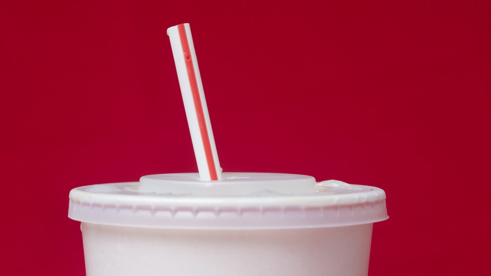 A paper cup with a plastic lid and straw