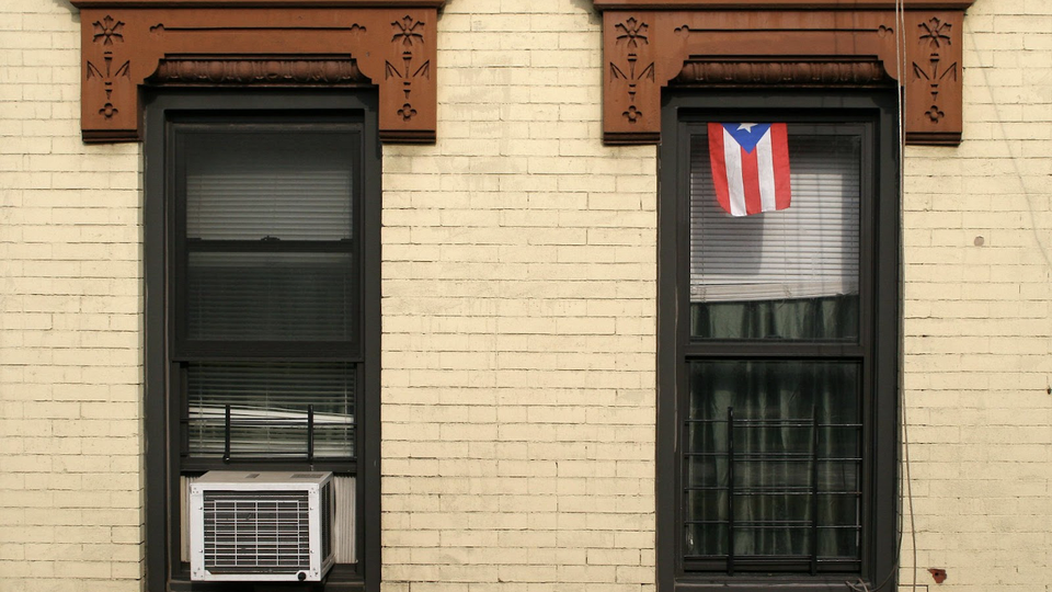 The flag of Puerto Rico hanging from a sash window of a house in Brooklyn, New York City