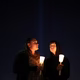 People hold candles at a vigil.