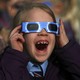 A pupil wears protective glasses as she views a partial solar eclipse from a school in Altrincham.