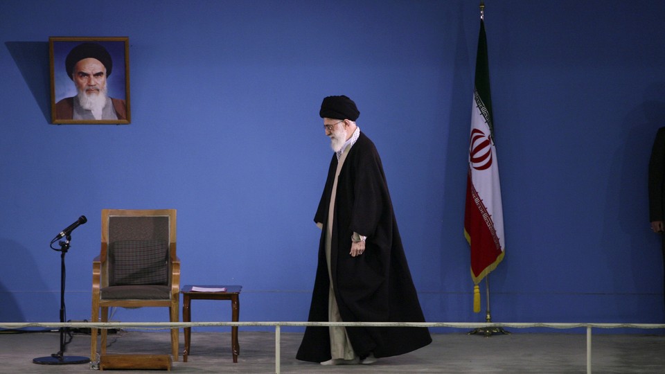 Ali Khamenei walking next to an empty chair