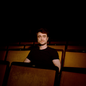 A photograph of actor Daniel Radcliffe Sitting in a theater seat.