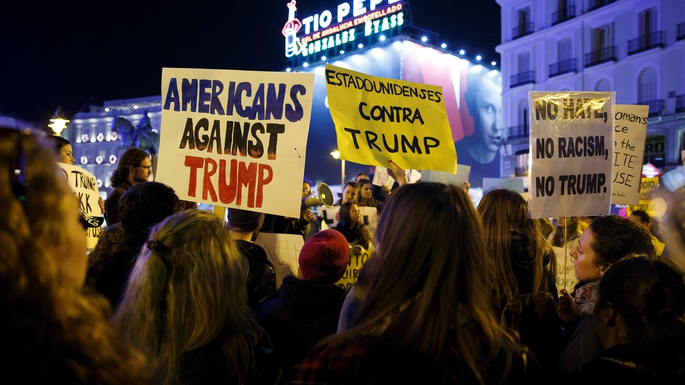 Demonstrators hold up signs during a protest against U.S. President-elect Donald Trump at the Puerta del Sol Square in central Madrid, Spain, December 2, 2016.