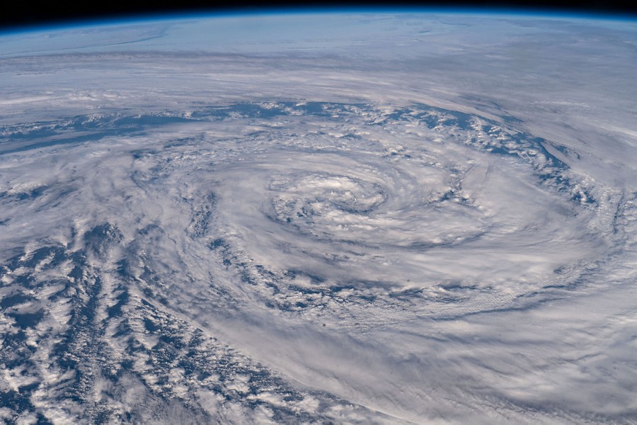 Clouds swirl in a spiral pattern, seen from orbit.