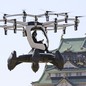 A person flies a small drone-like aircraft near a Japanese castle.