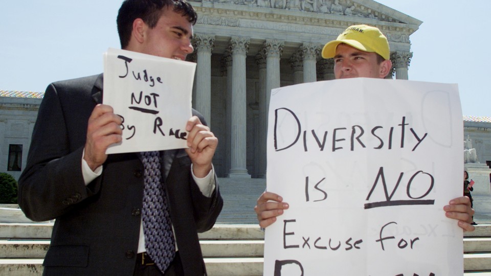 Two male students protest outside of the Supreme Court with signs accusing affirmative action of being racist.