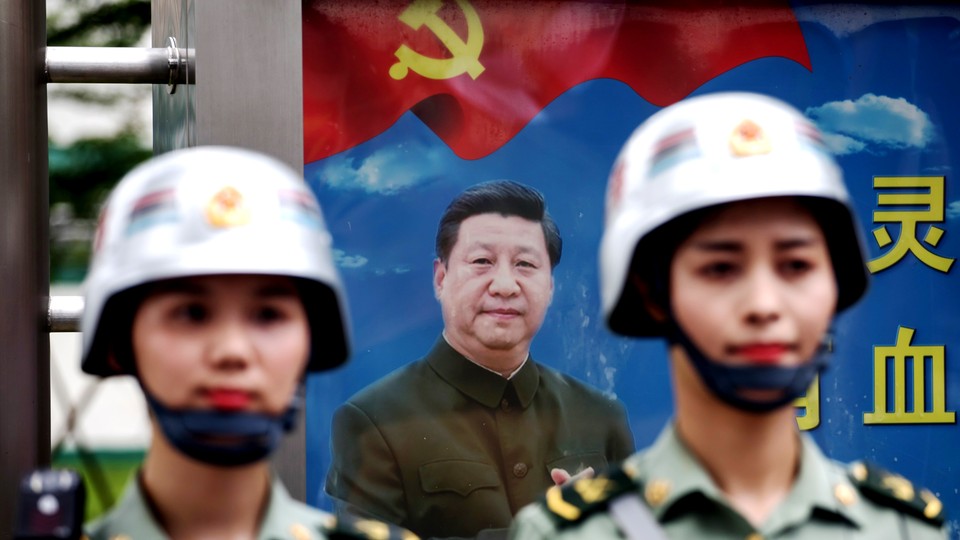 Members of the People's Liberation Army stand in front of a poster featuring Chinese President Xi Jinping.