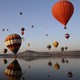 Hot-air balloons and their reflections along a coastline 