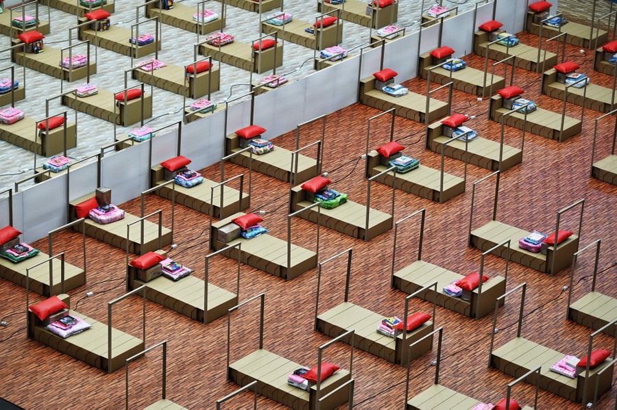 Rows of empty beds are set up inside a stadium.