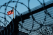 An American flag above a wire fence