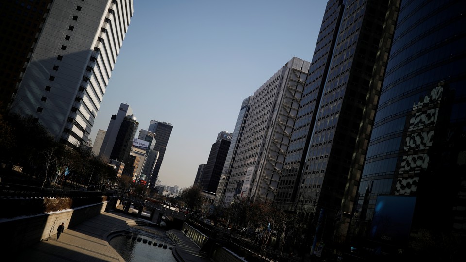 A man walks along a canal next to skyscrapers