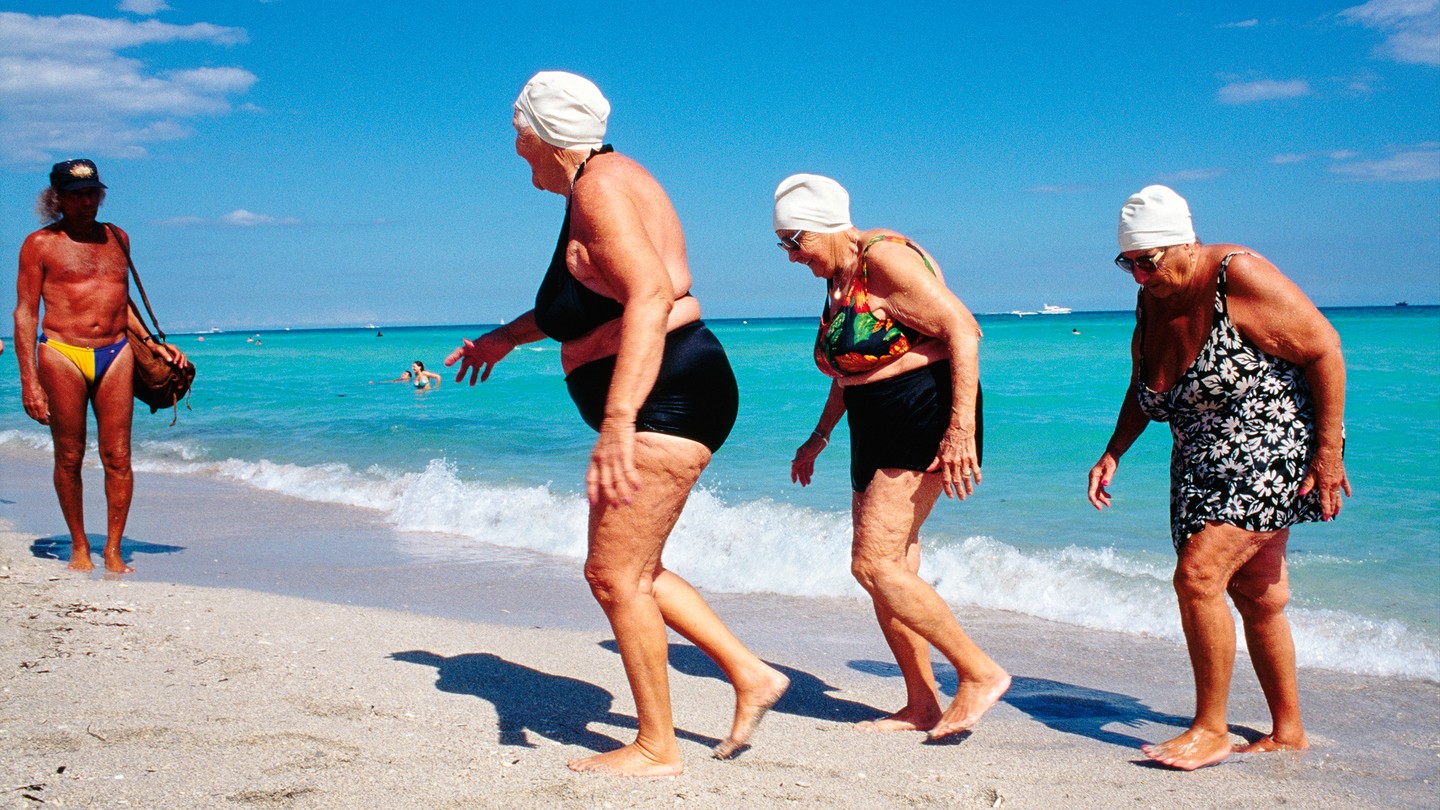 Ladies exiting the ocean looking at a man in a speedo