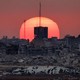 A photo of the sun setting behind destroyed buildings in Palestinian territory.