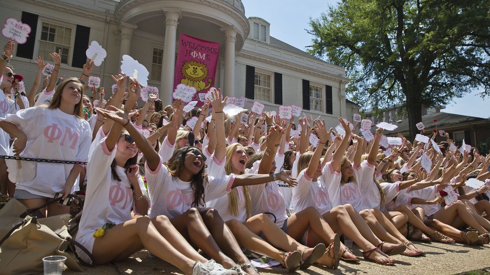 Members of the University of Alabama's Phi Mu chapter smile in front of their sorority house on bid day.