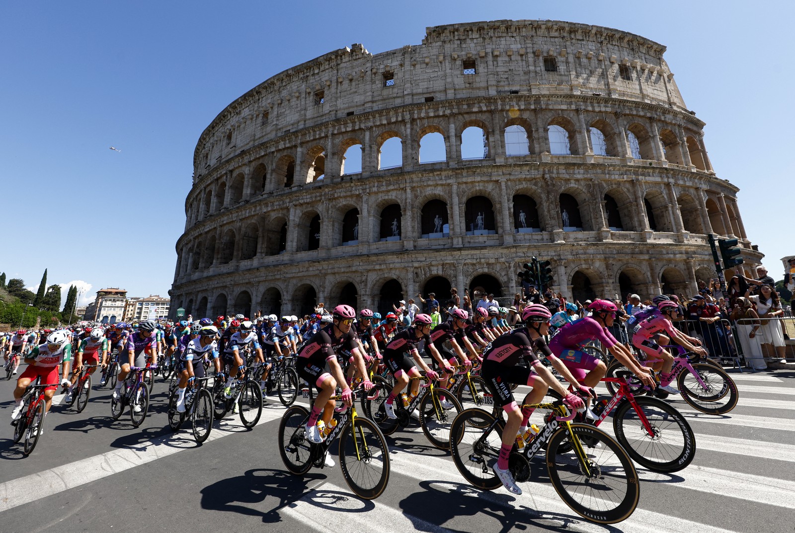 A pack of cyclists rides past the Colosseum in Rome.