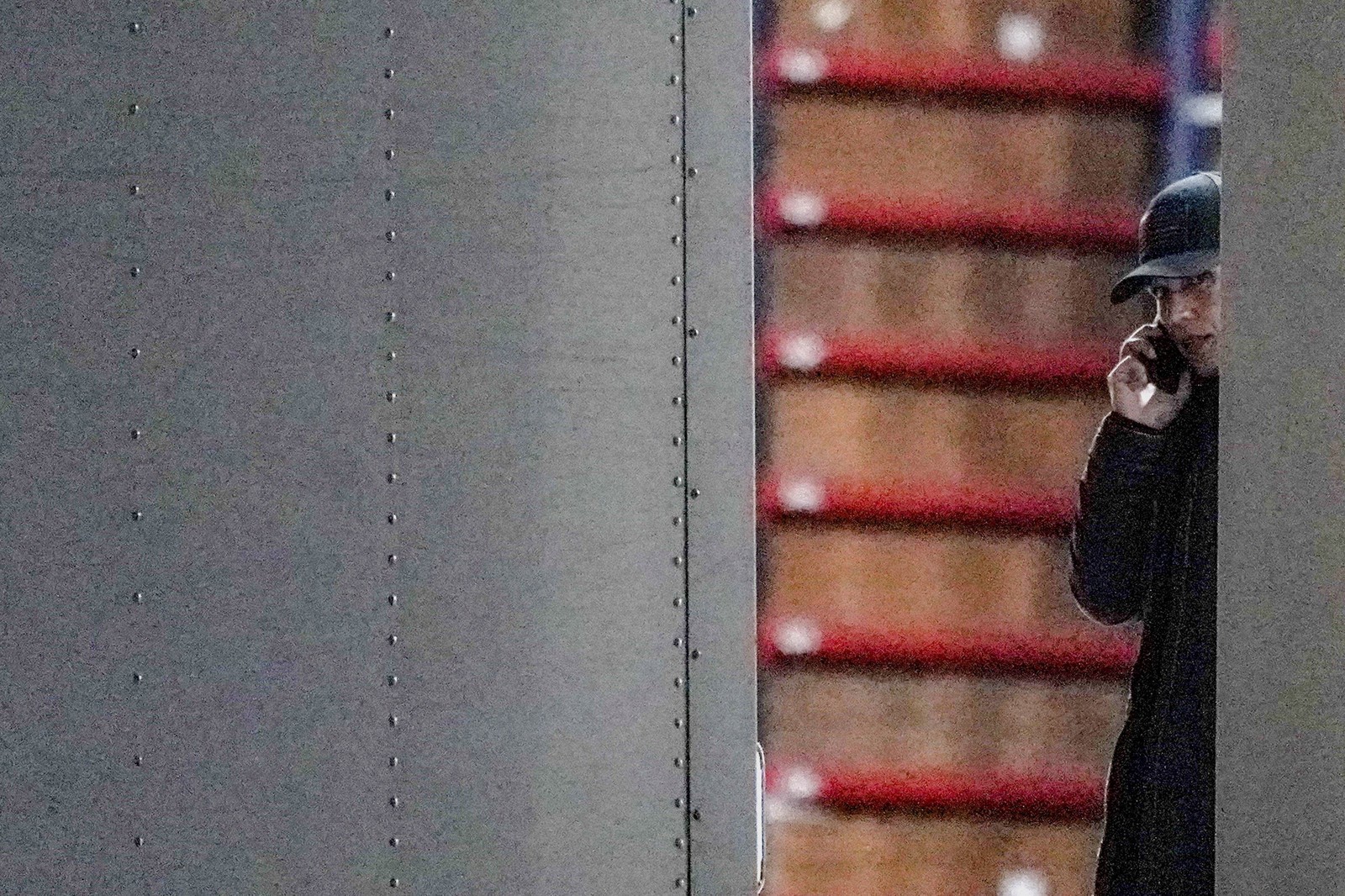 A person speaks on a phone, seen near stacked boxes.