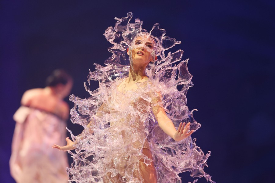 A model displays a garment of clear material that makes it look like they are inside a big splash of water.