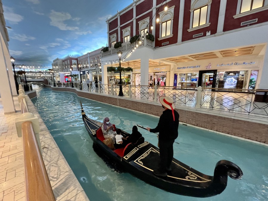 A gondolier ferries people on a canal inside a shopping mall.