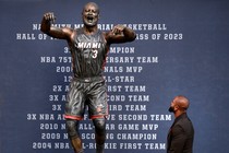 A color photo of Dwyane Wade looking up at the newly unveiled statue of himself.