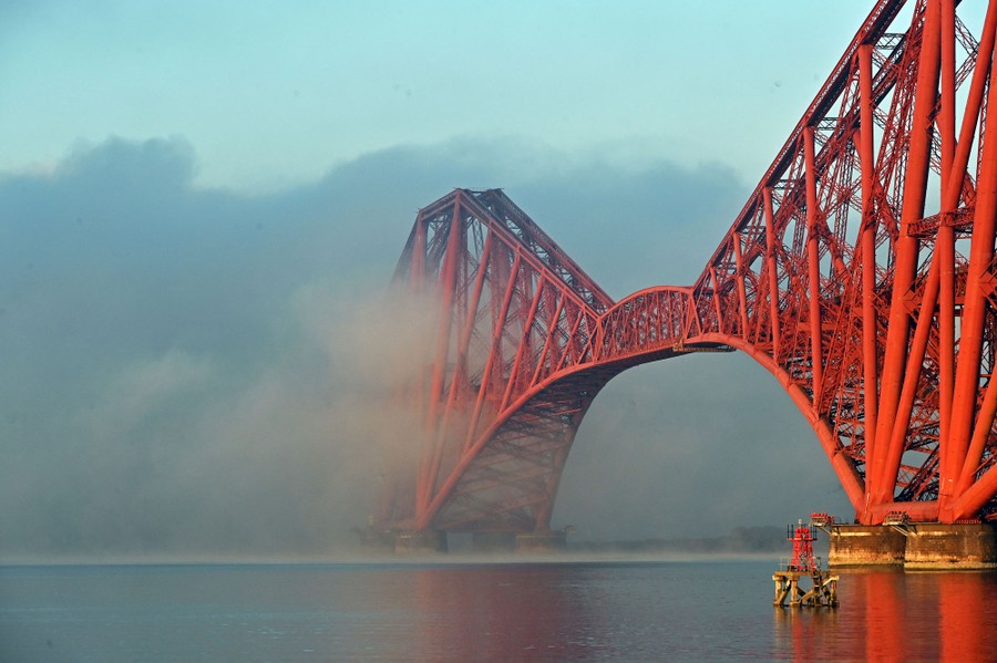 A long steel bridge is partially obscured by fog.