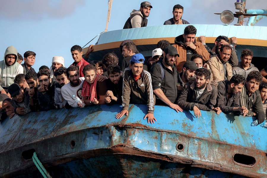 A couple dozen refugees gather at the front of a boat.